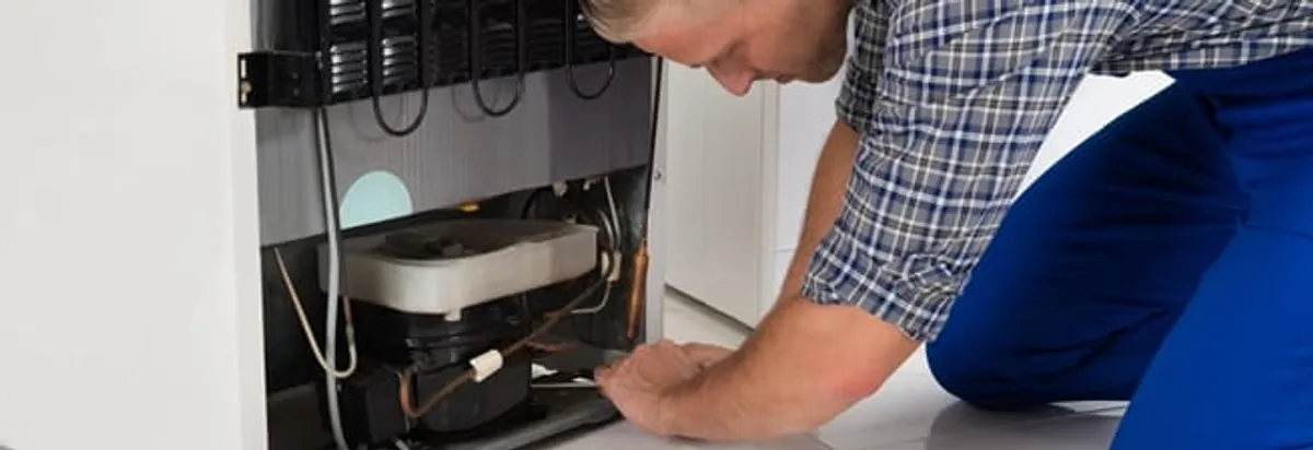 Refrigerator repair technician servicing the compressor and condenser area in Stamford, CT