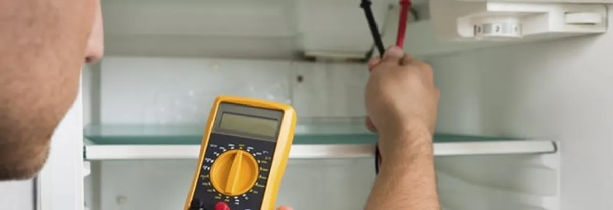 Refrigerator repair technician testing electrical components with a multimeter in Stamford, CT