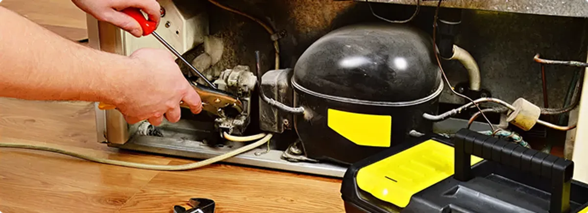 Refrigerator repair technician fixing the compressor and wiring in Stamford, CT